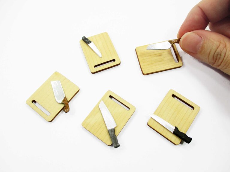 Handcrafted 1:12 scale miniature wooden cutting board and tiny knives for dollhouse kitchen prep scenes.