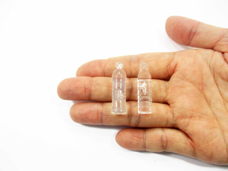 Palm holding two clear miniature water bottles, round and square styles, showing realistic 1:6 scale for fashion dolls.