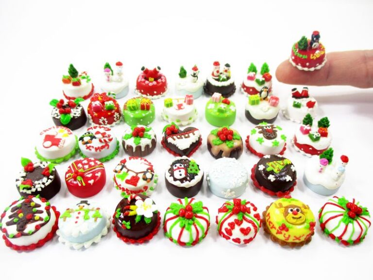 Handheld view of lot 1:12 scale miniature Christmas clay cakes with green icing and red berries for dollhouse bakery.